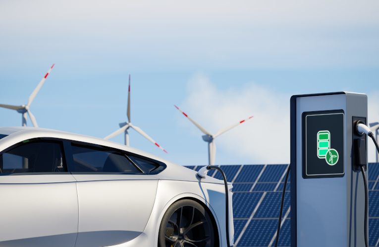 Electric vehicle charging with solar panels and wind turbines in the background.